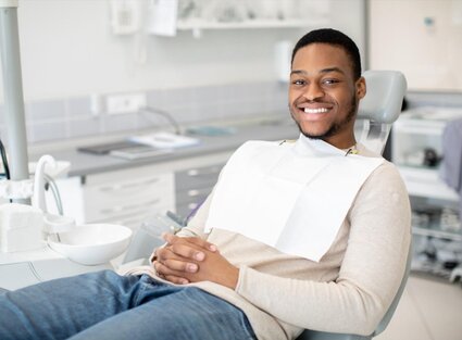 black man smiling wearing dental bib, sitting in dental exam chair, dentist Frederick, MD general dentistry