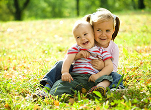boy and girl sitting in grass outside smiling, pediatric dentistry Frederick, MD children's dentist
