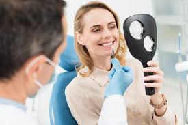 woman at dentist looking at herself in handheld mirror, dental implants Melrose, MA