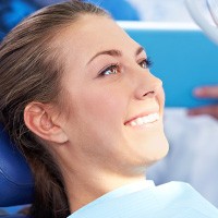 woman sitting in dental chair smiling, prepping for cosmetic dentistry Melrose, MA