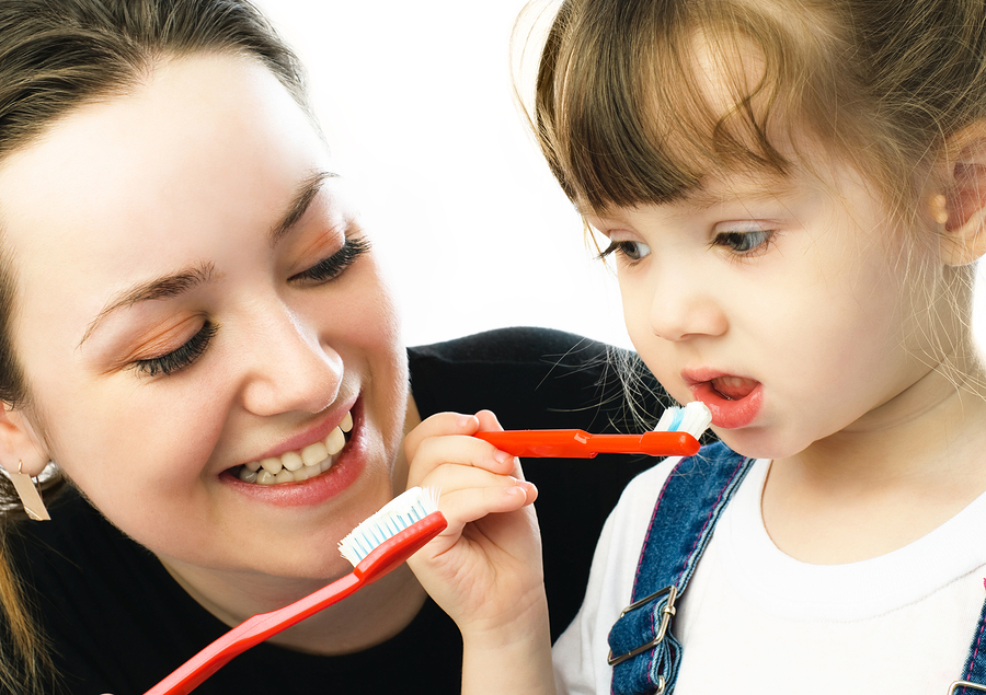 woman showing toddler girl how to brush her teeth with a toothbrush, children's dentist North York, ON