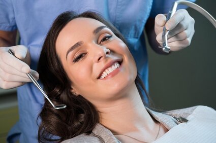 woman smiling, dentist behind her holding dental tools near mouth, teeth cleaning North York dentist
