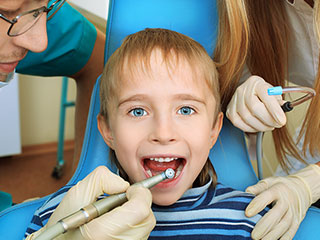 young blond boy with mouth open as North York dentist works on his teeth. Pediatric Dentistry North York, ON children's dentist