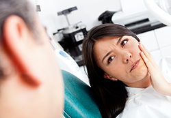 lady in dentist office holding jaw looking at doctor