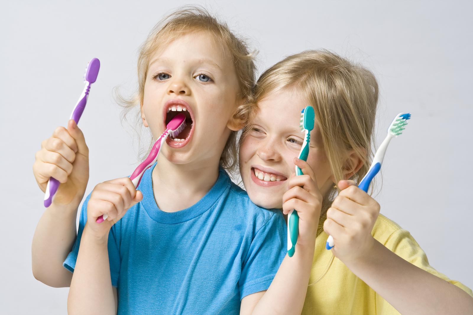 two blond children holding toothbrushes and pretending to brush teeth, Pediatric Dentistry University City, MO dentist