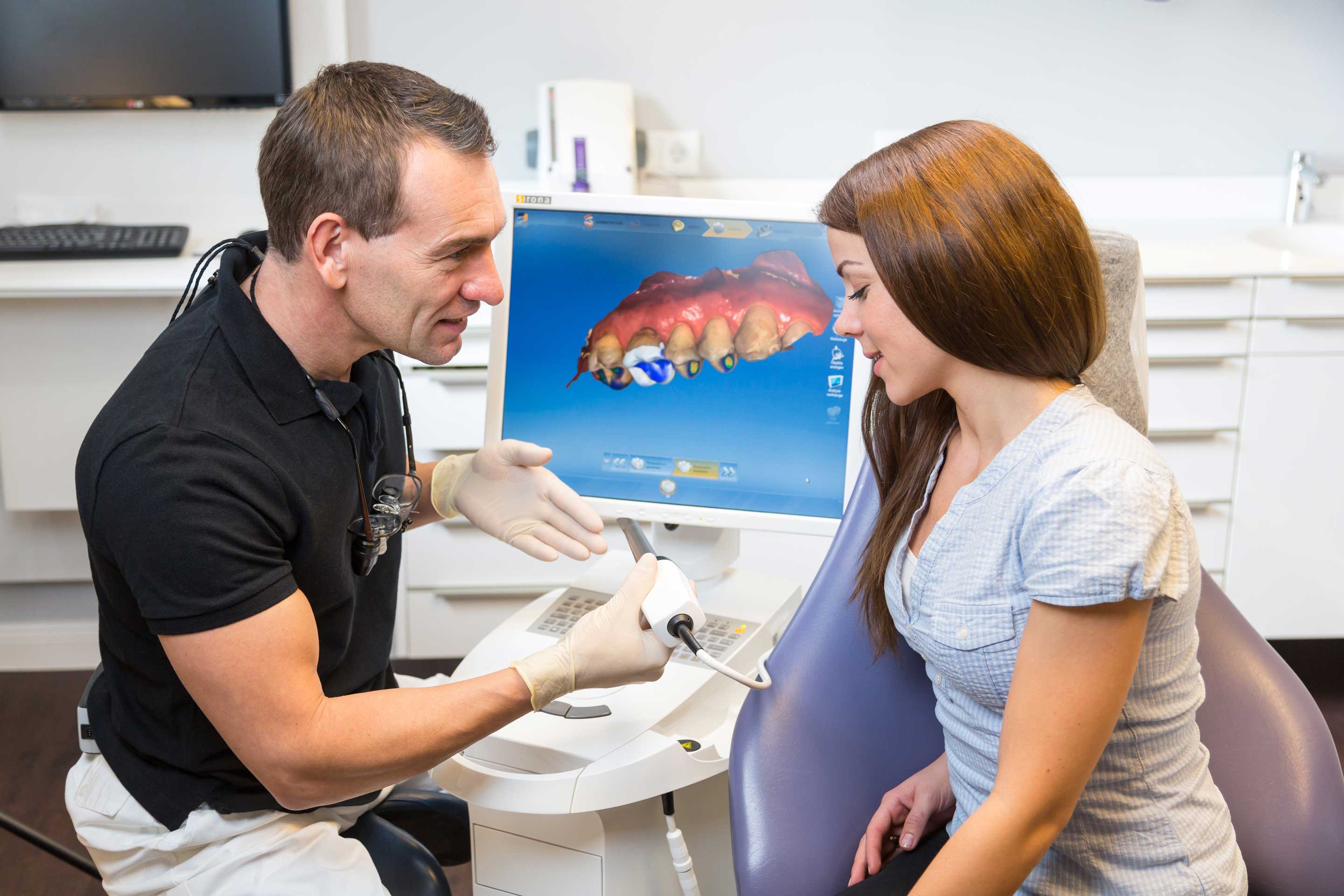 male dentist sitting at CEREC computer going over same day crown process with female patient, dentist Verona, PA