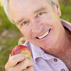 Old man holding apple Dental Implants Cypress, TX