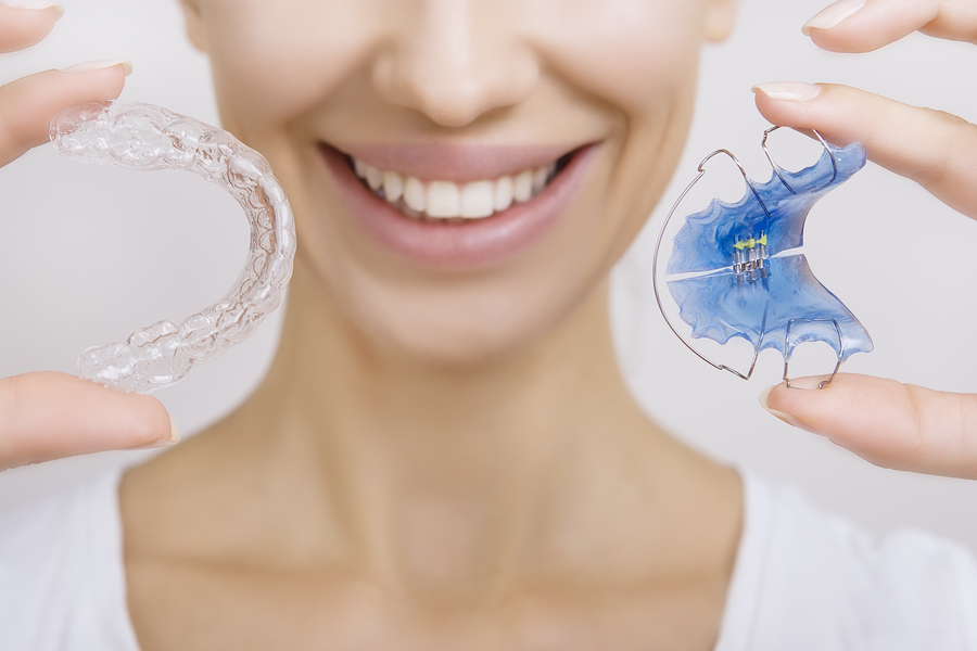 Photograph of smiling woman holding various Orthodontics devices in Harper Woods, MI and West Bloomfield, MI