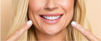woman pointing two fingers at her smile showing Dental Implants Manteca, CA dentist