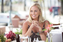 woman sitting at a restaurant table outdoors, smiling Invisalign Cumberland Park SA dentist