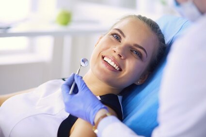 blond teen girl smiling, wearing dental bib lying back in exam chair, teeth cleaning Edison, NJ dentist