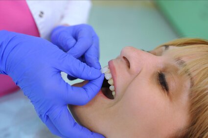 dentist's gloved hand placing veneer pieces onto woman's front teeth, veneers Sherman Oaks, CA cosmetic dentistry dentist's gloved hand placing veneer pieces onto woman's front teeth, veneers Sherman Oaks, CA cosmetic dentistry